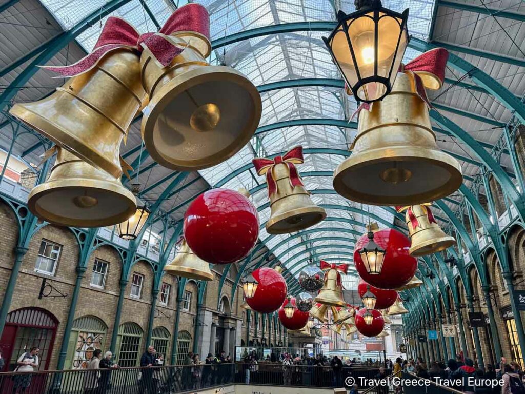 The interiors of the Covent Garden Market with Large Bells and ornaments in red and gold suspended from the ceiling